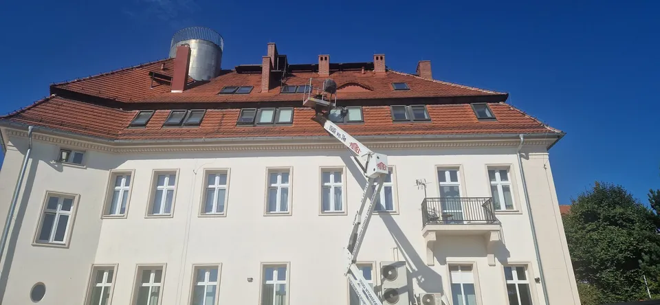 Podnośnik koszowy PIOTREX przy dachu kamienicy